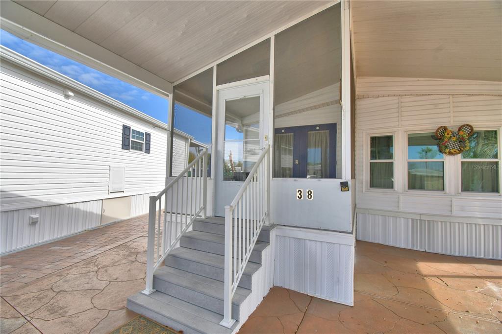 A set of gray stairs leads to a screened-in porch entrance on a mobile home — 9000 US HIGHWAY 192 UNIT 38, CLERMONT, FL