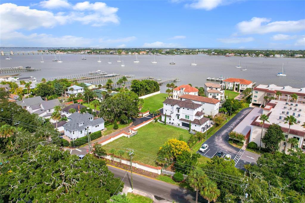 An aerial view shows a waterfront property with a large lawn, houses, and sailboats nearby — 1 SOUTH STREET UNIT A & B, ST AUGUSTINE, FL