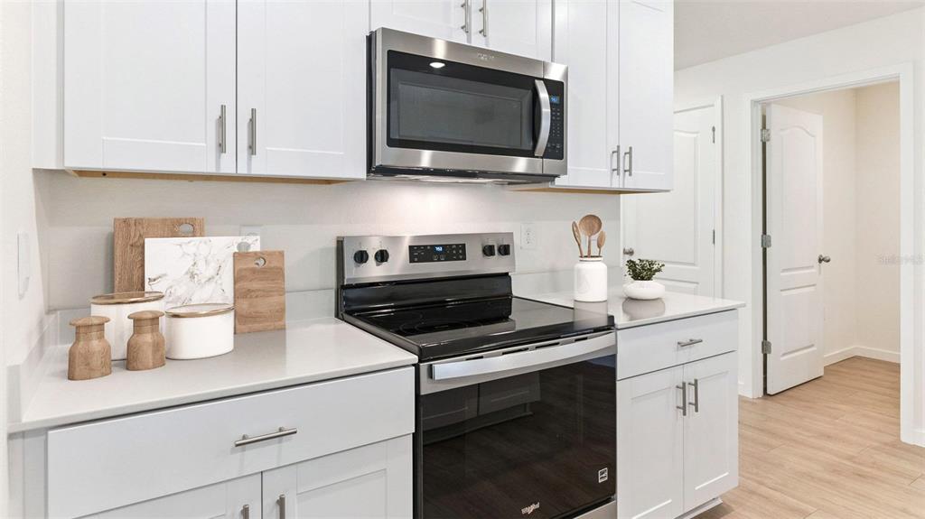 A kitchen features white cabinets, stainless steel appliances, and light gray countertops — 133 HEIRLOOM DRIVE, ORMOND BEACH, FL