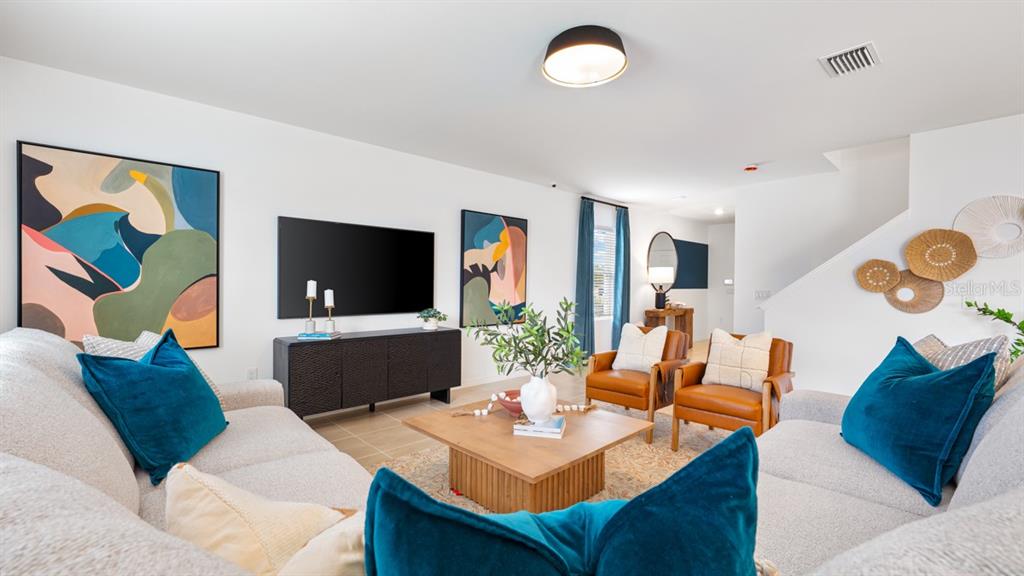 A living room features two sofas, two leather armchairs, a coffee table, and abstract wall art — 13741 SQUALL LANE, HUDSON, FL