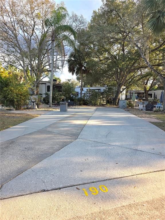 A concrete driveway with the number 190 painted in yellow leads to a parked RV — 190 LONGHORN DRIVE, LAKE WALES, FL