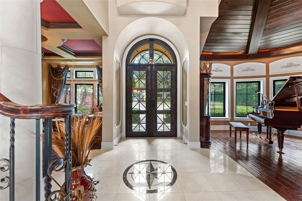 A grand foyer features a tiled floor with a compass inlay and double arched doors — 5070 DOWN POINT LANE, WINDERMERE, FL