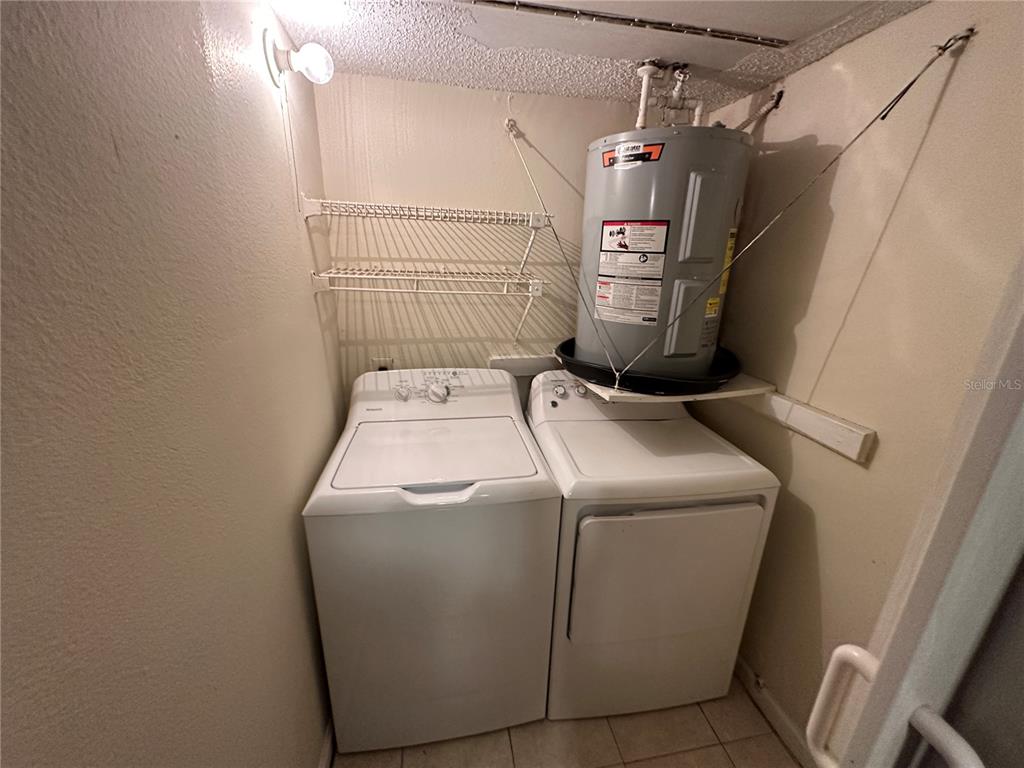 A laundry closet contains a washing machine, a dryer, and a water heater on a shelf — 1940 LAKE ATRIUMS CIRCLE UNIT 89, ORLANDO, FL
