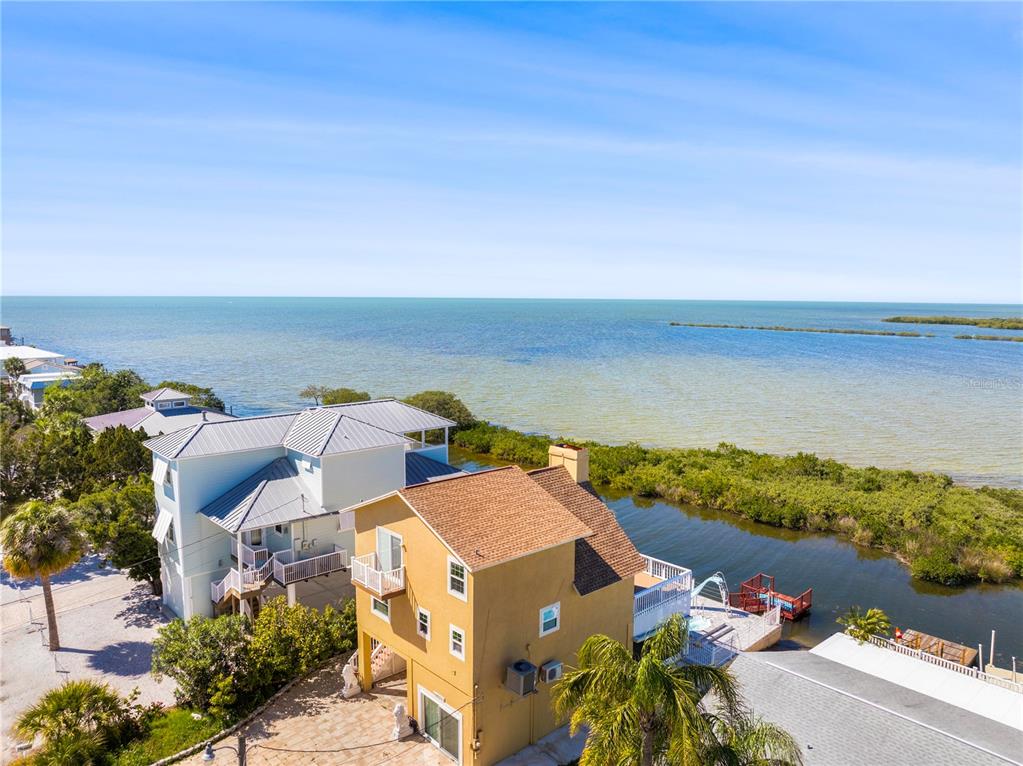 An aerial view shows two multi-story houses situated along a canal leading to the ocean — 6633 DRIFTWOOD DRIVE, HUDSON, FL