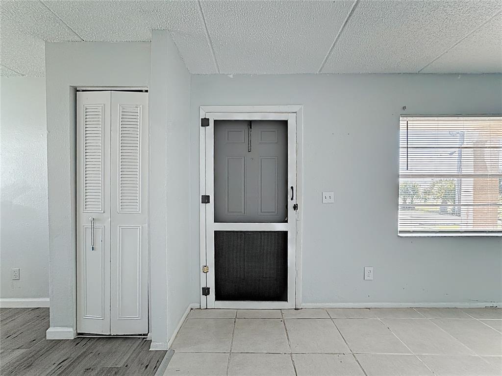 A room with light-colored walls, tiled flooring, a white louvered closet door, and a screen door — 694 MICHIGAN COURT UNIT 2, ST CLOUD, FL