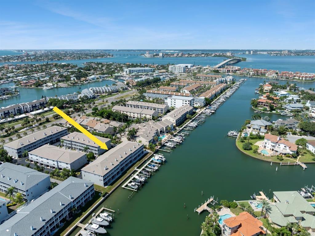 An aerial view shows multi-story waterfront condominium buildings with boat slips along a canal — 521 PINELLAS BAYWAY S UNIT 105, TIERRA VERDE, FL