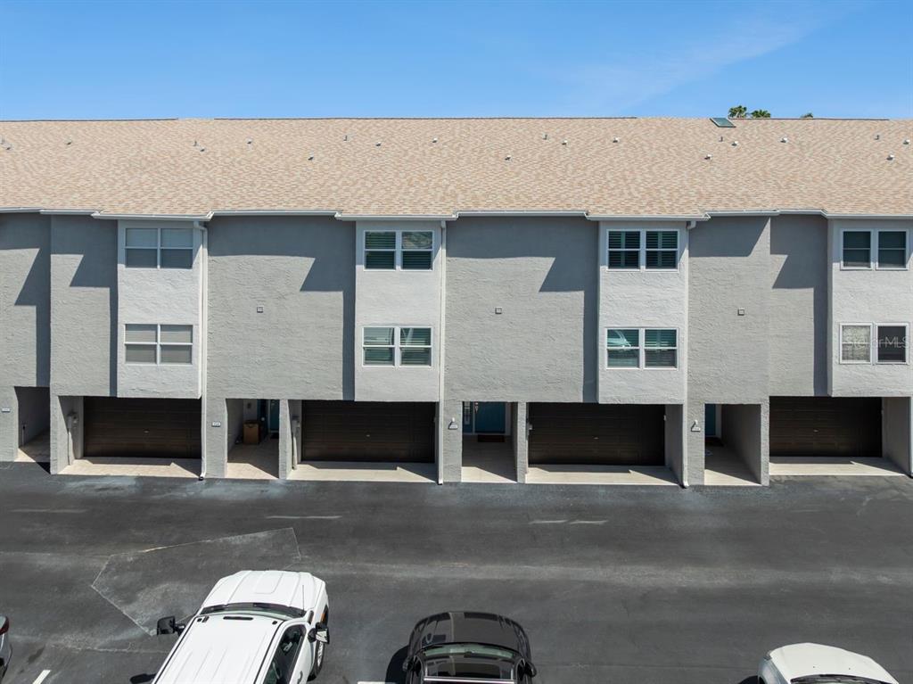 An exterior view of a multi-unit townhouse complex with gray stucco walls and brown garages — 521 PINELLAS BAYWAY S UNIT 105, TIERRA VERDE, FL