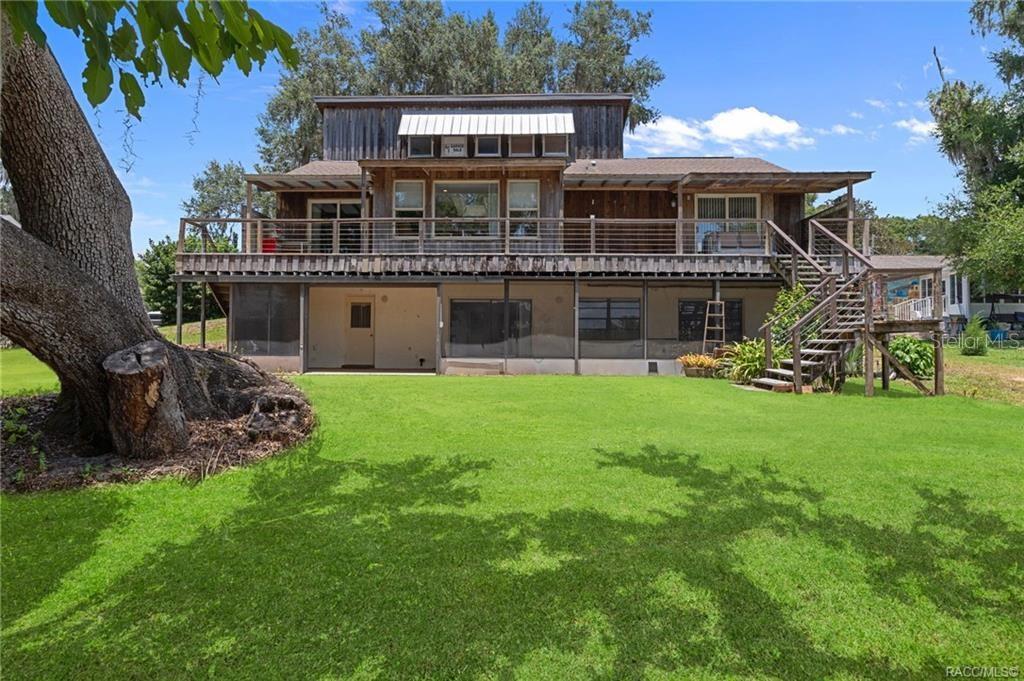 A two-story wooden house with a large deck and a screened-in ground floor patio — 7514 E BROYHILL PLACE, INVERNESS, FL