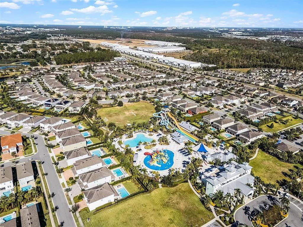 An aerial view shows a residential neighborhood featuring a large community pool with water slides — 310 PENDANT COURT, KISSIMMEE, FL