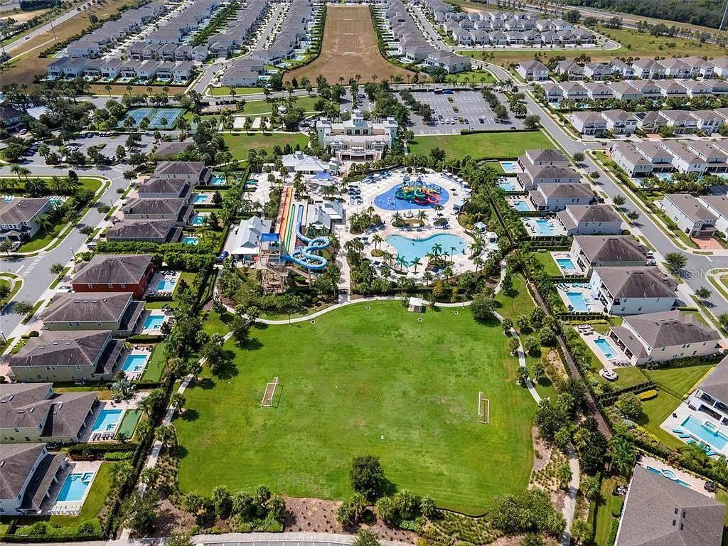Aerial view of a residential community featuring a large pool, water slides, and sports field — 310 PENDANT COURT, KISSIMMEE, FL