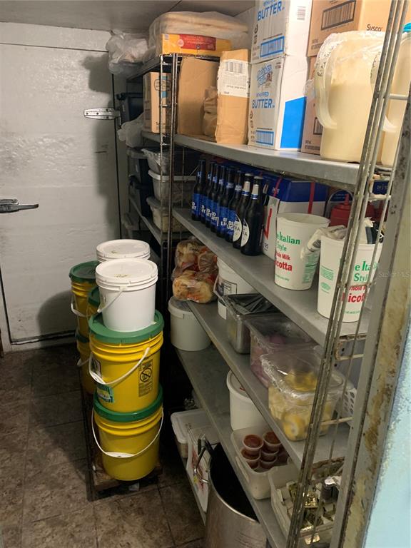 A walk-in cooler contains metal shelving units stocked with food supplies and plastic buckets — 2110 SARNO ROAD, MELBOURNE, FL