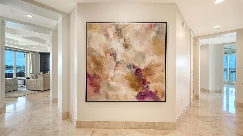 A hallway with marble floors features a large abstract painting on the central wall — 464 GOLDEN GATE POINT UNIT 702, SARASOTA, FL