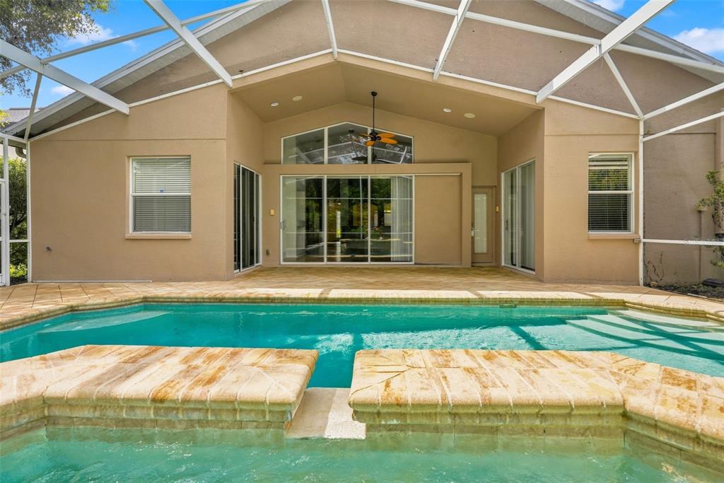 A swimming pool and spa sit on a paved patio beneath a screened-in lanai enclosure — 27417 SILVER THATCH DRIVE, WESLEY CHAPEL, FL