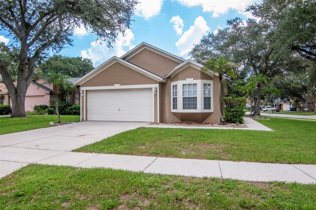 A tan single-story house with a two-car garage and a bay window in the front — 1914 BRANDON BROOK ROAD, VALRICO, FL