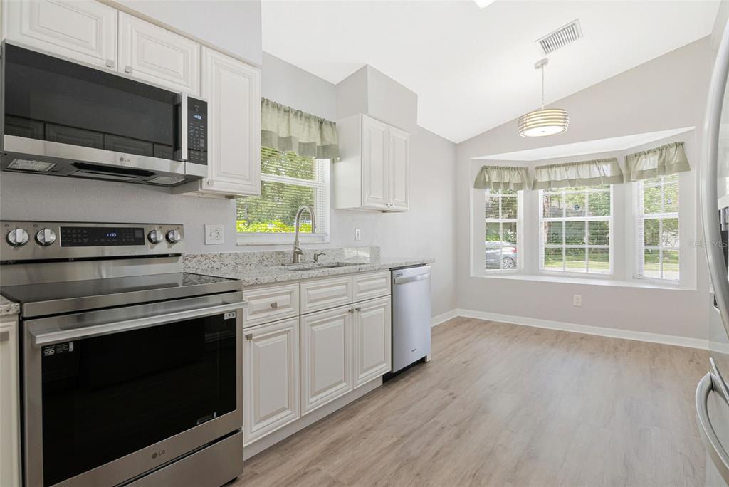 A kitchen with white cabinets, stainless steel appliances, granite countertops, and a bay window area — 1914 BRANDON BROOK ROAD, VALRICO, FL