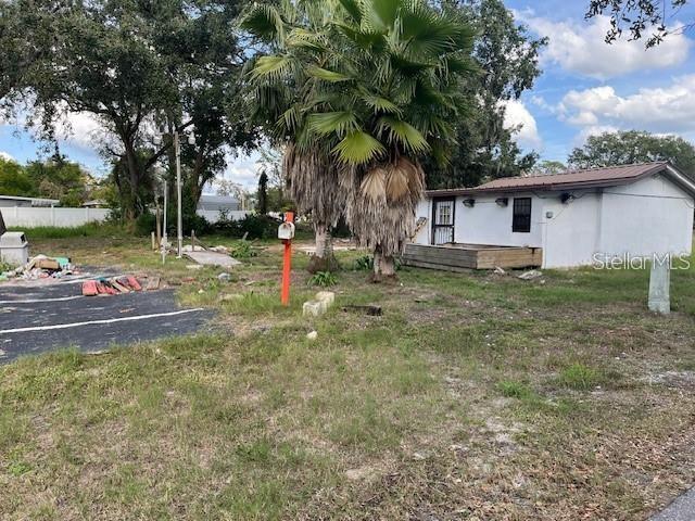 A small, light-colored building sits next to a large palm tree on a grassy lot — 7502 N 40TH STREET, TAMPA, FL