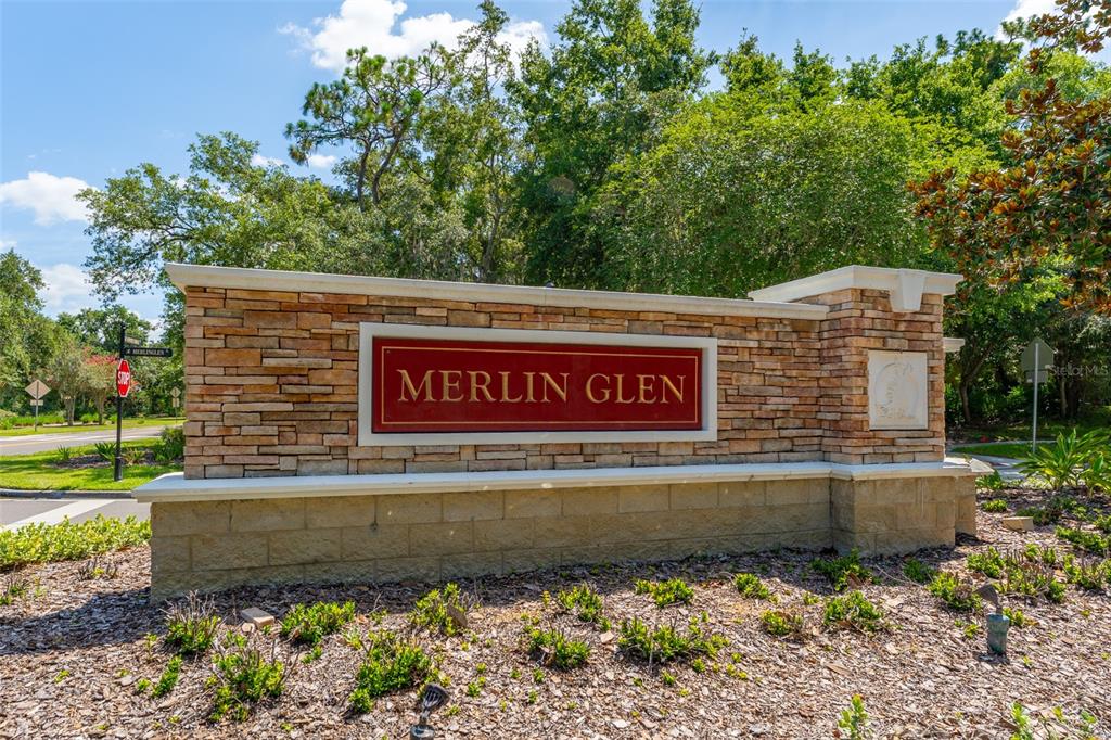A stone monument sign for Merlin Glen stands in a landscaped area with trees — 15211 MERLINGLEN PLACE, LITHIA, FL