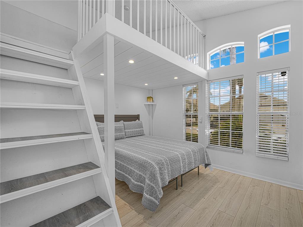 A bedroom features a queen bed, a loft area with a railing, and white stairs — 16809 GLENBROOK BOULEVARD, CLERMONT, FL