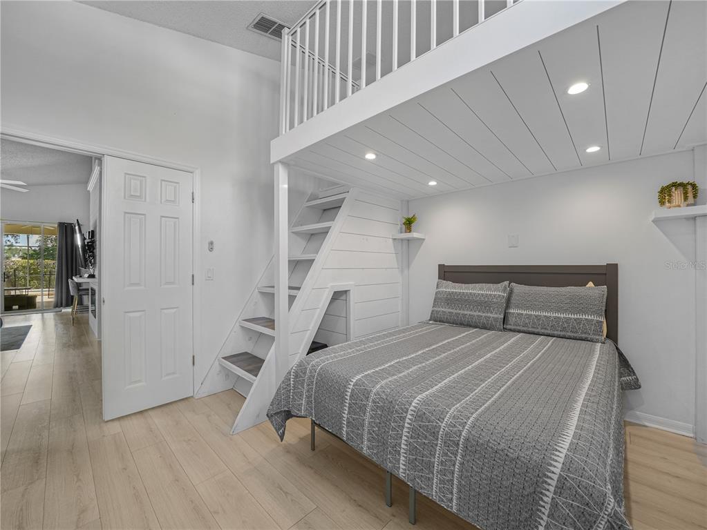 A bedroom features a loft bed with a built-in staircase and light wood flooring — 16809 GLENBROOK BOULEVARD, CLERMONT, FL
