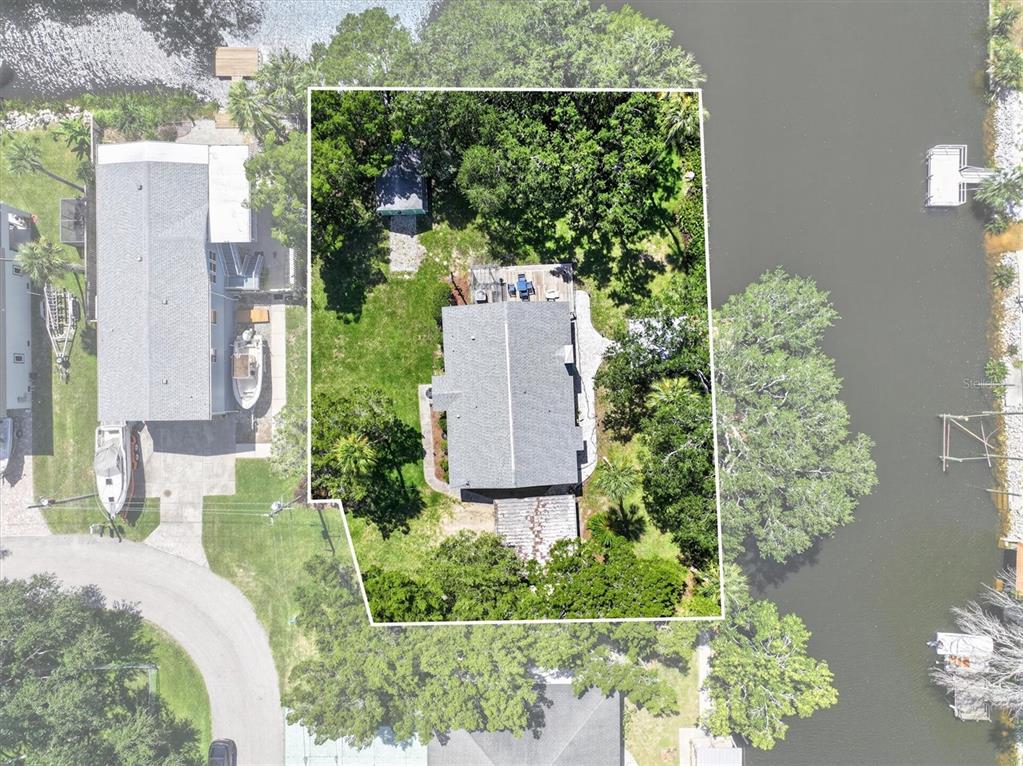 An aerial view shows a house with a gray roof surrounded by trees and water — 6086 ISLAND DRIVE, WEEKI WACHEE, FL