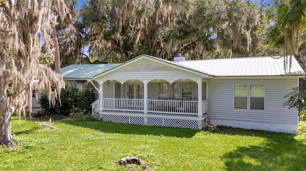 A wooden deck with two chairs overlooks a grassy yard surrounded by trees with Spanish moss — 20361 1ST STREET, MC INTOSH, FL