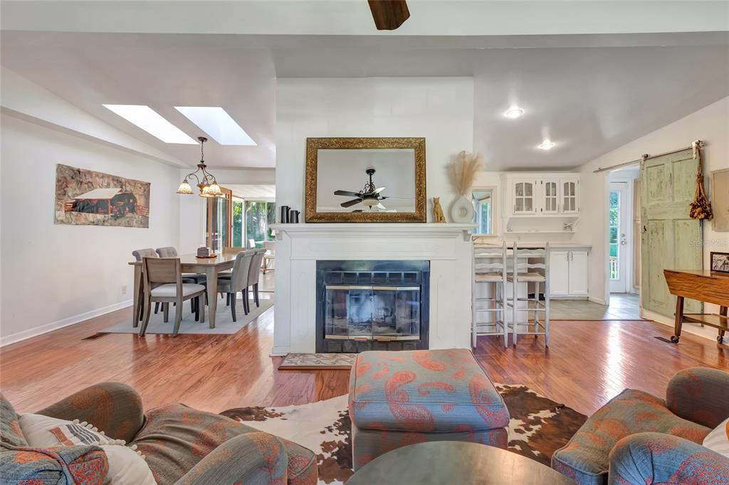 A living room with a fireplace, dining area, and kitchen featuring hardwood floors — 20361 1ST STREET, MC INTOSH, FL