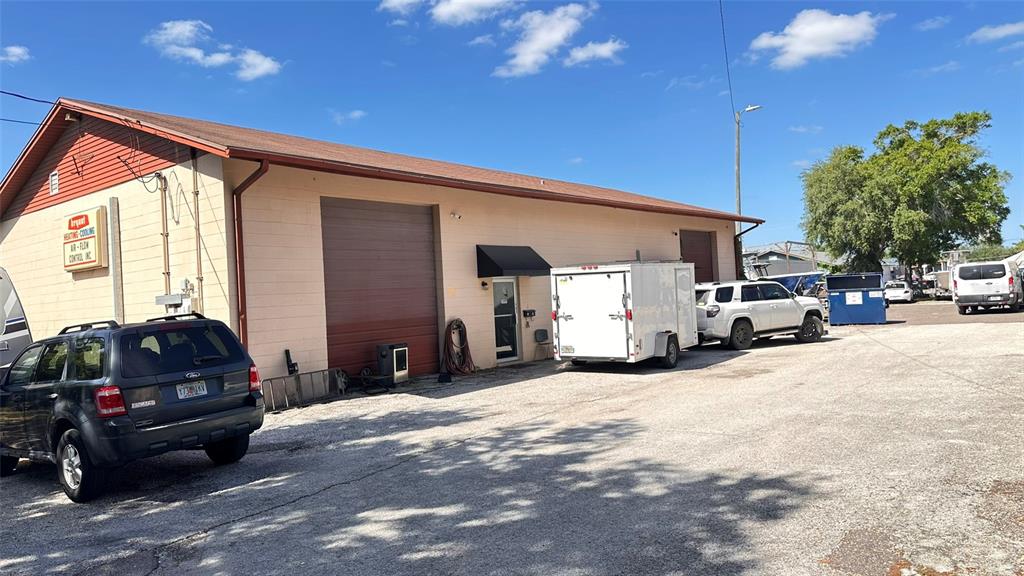 A single-story commercial building with a tan facade, two large roll-up doors, and a parking lot — 4712 N CLARK AVENUE, TAMPA, FL