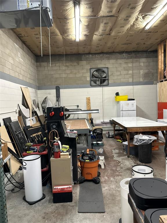 A cluttered workshop features a large industrial machine, a work table, and exposed ceiling insulation — 4712 N CLARK AVENUE, TAMPA, FL