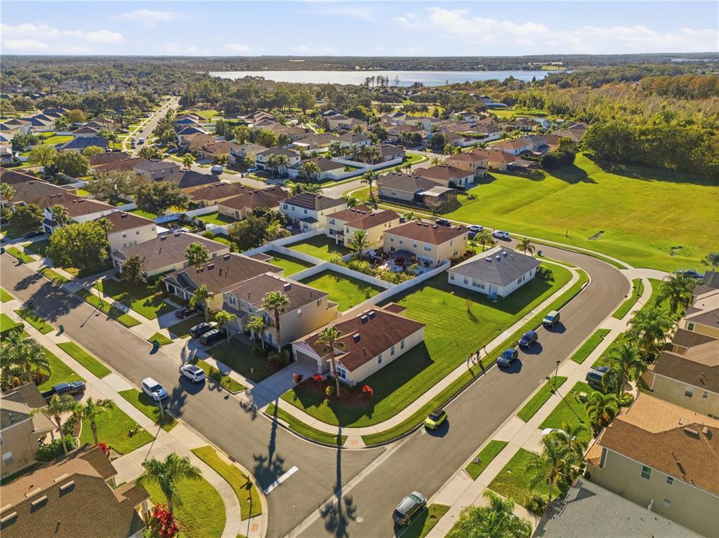 An aerial view shows a suburban neighborhood with houses, manicured lawns, and a distant lake — 502 FIRST CAPE CORAL DR, WINTER GARDEN, FL