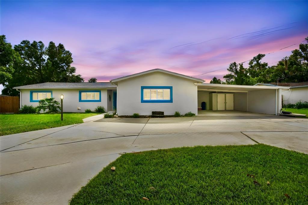 A single-story house with a white exterior, blue window trim, and an attached carport — 1303 SE KINGS BAY DRIVE, CRYSTAL RIVER, FL