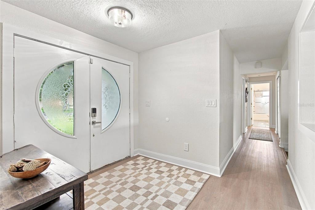 An entryway features white double doors with circular glass inserts, light wood flooring, and a rug — 1303 SE KINGS BAY DRIVE, CRYSTAL RIVER, FL