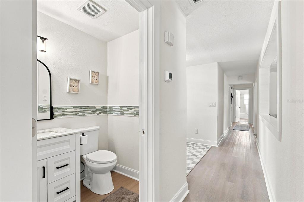 A small bathroom with a white vanity and toilet opens into a long, light-floored hallway — 1303 SE KINGS BAY DRIVE, CRYSTAL RIVER, FL