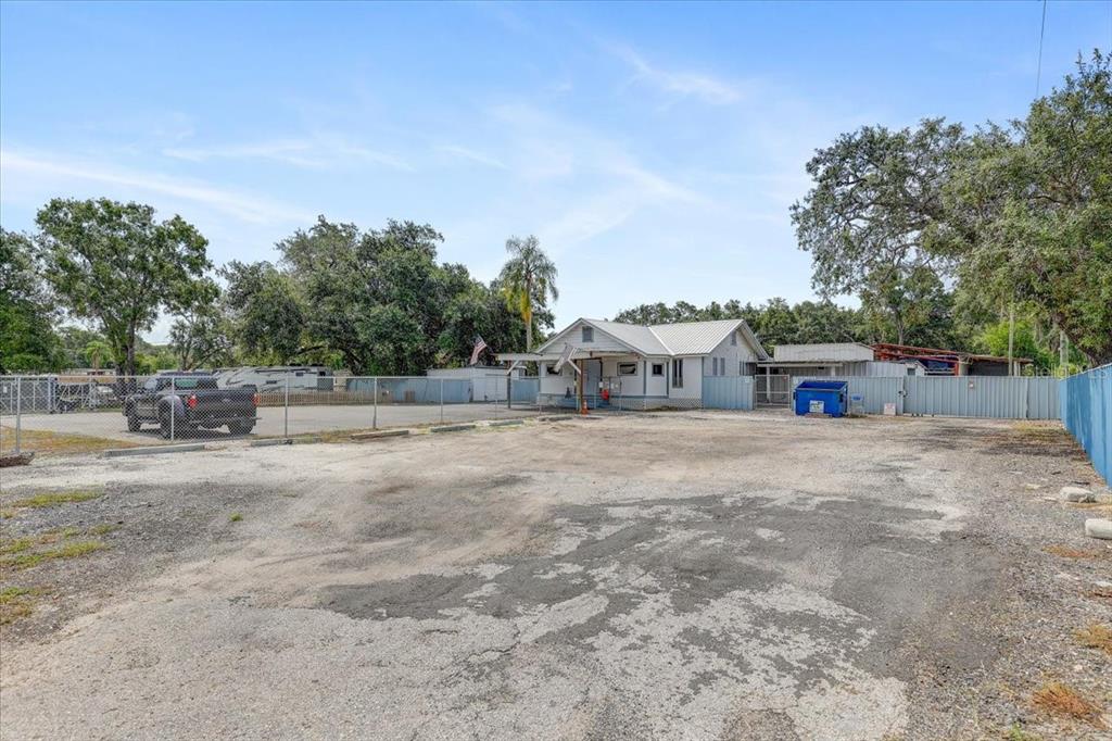 A gravel lot leads to a small, light-colored house enclosed by a chain-link fence — 11309 E 92 HIGHWAY, SEFFNER, FL