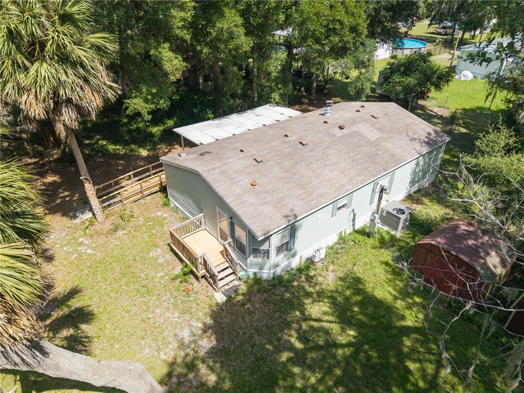 An aerial view shows a light green manufactured home with a shingled roof and wooden deck — 2786 NE 33RD PLACE, COLEMAN, FL
