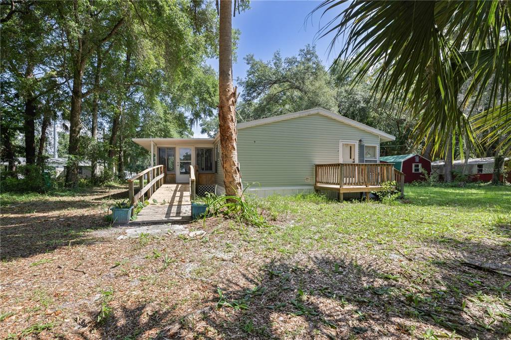 A light green mobile home features a wooden wheelchair ramp and a small back deck — 2786 NE 33RD PLACE, COLEMAN, FL