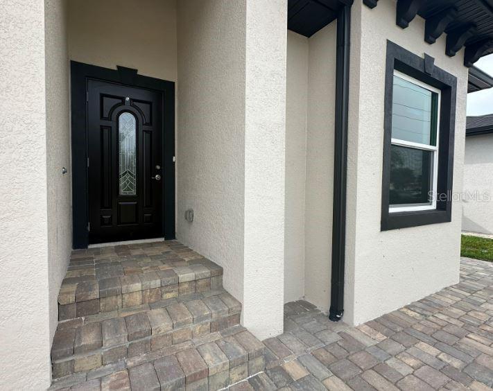 A black front door with a glass insert sits above stone steps at an entrance — 57 BOUNDARY BOULEVARD UNIT 2, ROTONDA WEST, FL