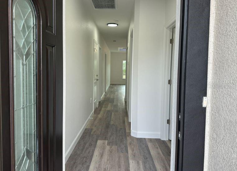 A view from an entryway looking down a long hallway with wood-look flooring — 57 BOUNDARY BOULEVARD UNIT 2, ROTONDA WEST, FL