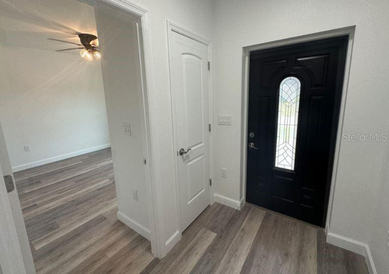 An entryway with a black front door, a white interior door, and light wood-look flooring — 57 BOUNDARY BOULEVARD UNIT 2, ROTONDA WEST, FL