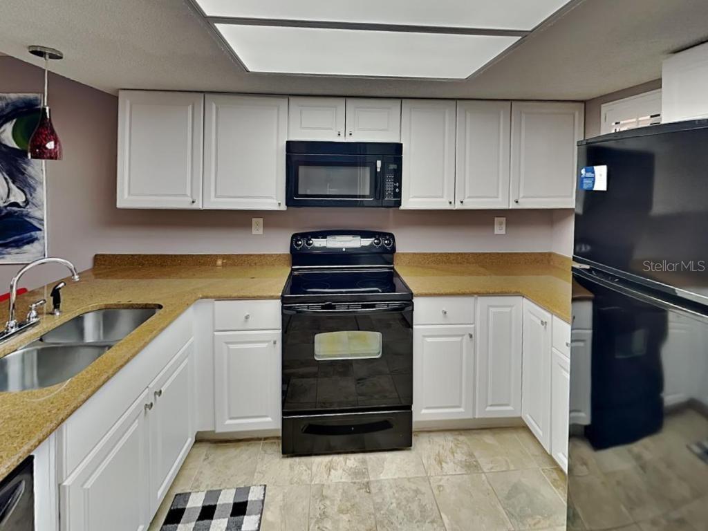 A kitchen with white cabinets, black appliances, and tan countertops under a recessed light fixture — 4250 A1A S UNIT K12, ST AUGUSTINE, FL