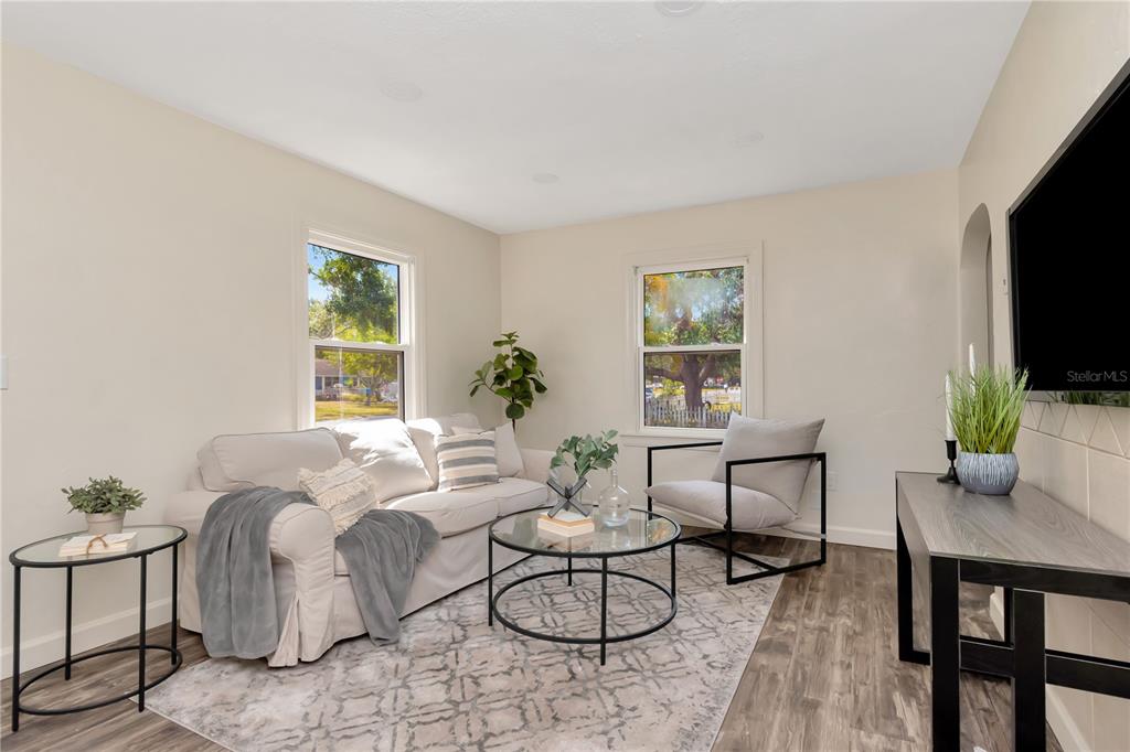 A living room features a white sofa, a glass coffee table, and an armchair on a rug — 1419 55TH STREET S, GULFPORT, FL
