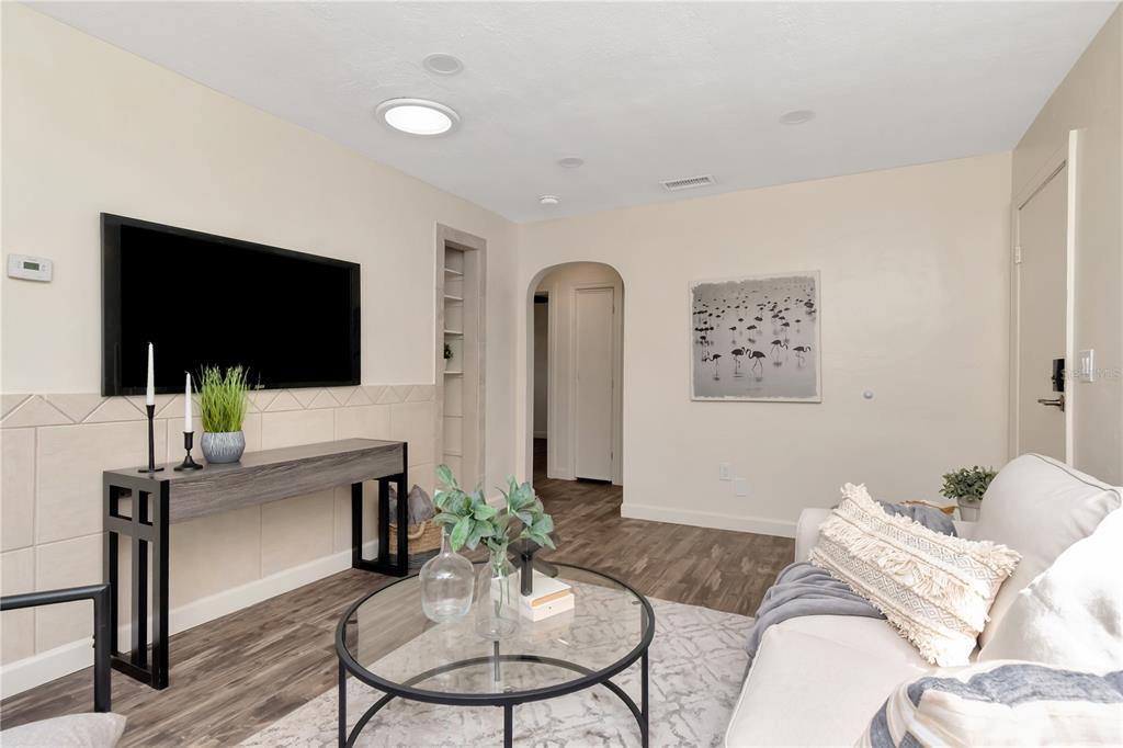 A living room features a wall-mounted television, a console table, and a glass coffee table — 1419 55TH STREET S, GULFPORT, FL