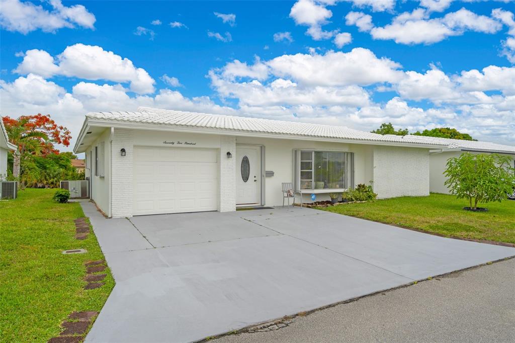 A single-story white house with a garage, driveway, and lawn under a blue sky — 7500 NW 66TH TERRACE, TAMARAC, FL