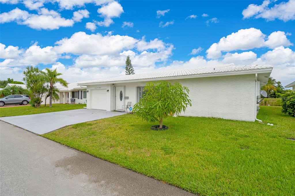 A white single-story house with a garage and a green lawn under a blue sky — 7500 NW 66TH TERRACE, TAMARAC, FL