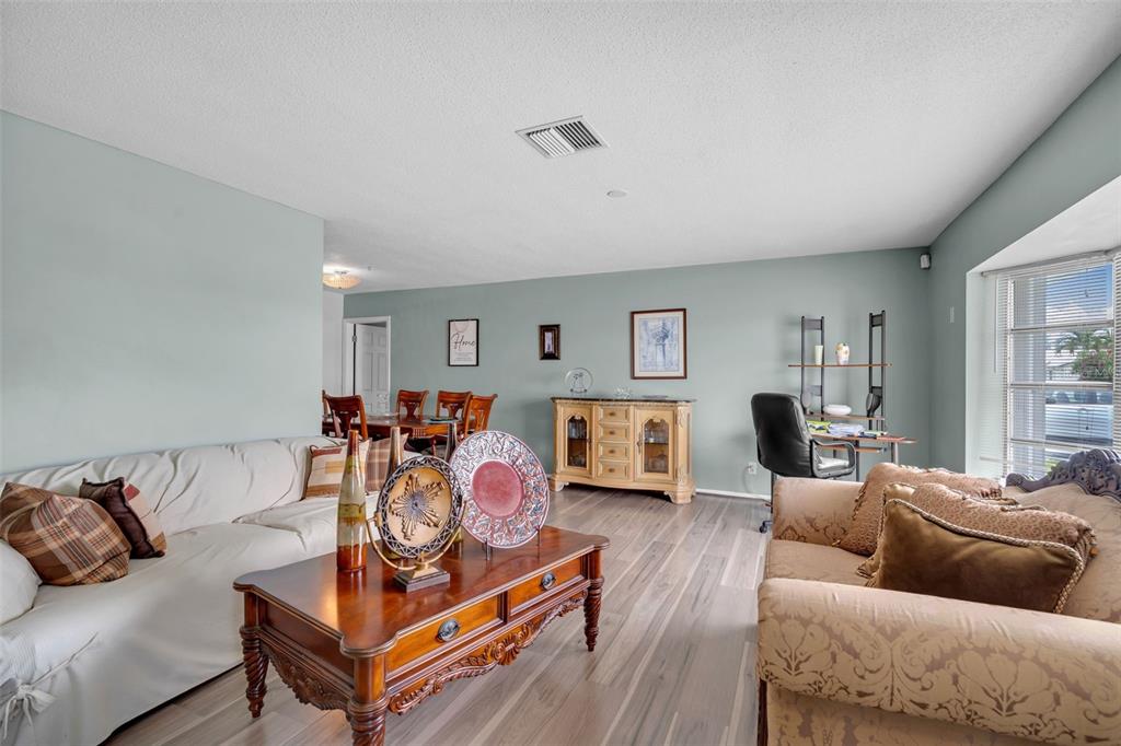 A living room features light blue walls, wood-look flooring, a coffee table, and two sofas — 7500 NW 66TH TERRACE, TAMARAC, FL