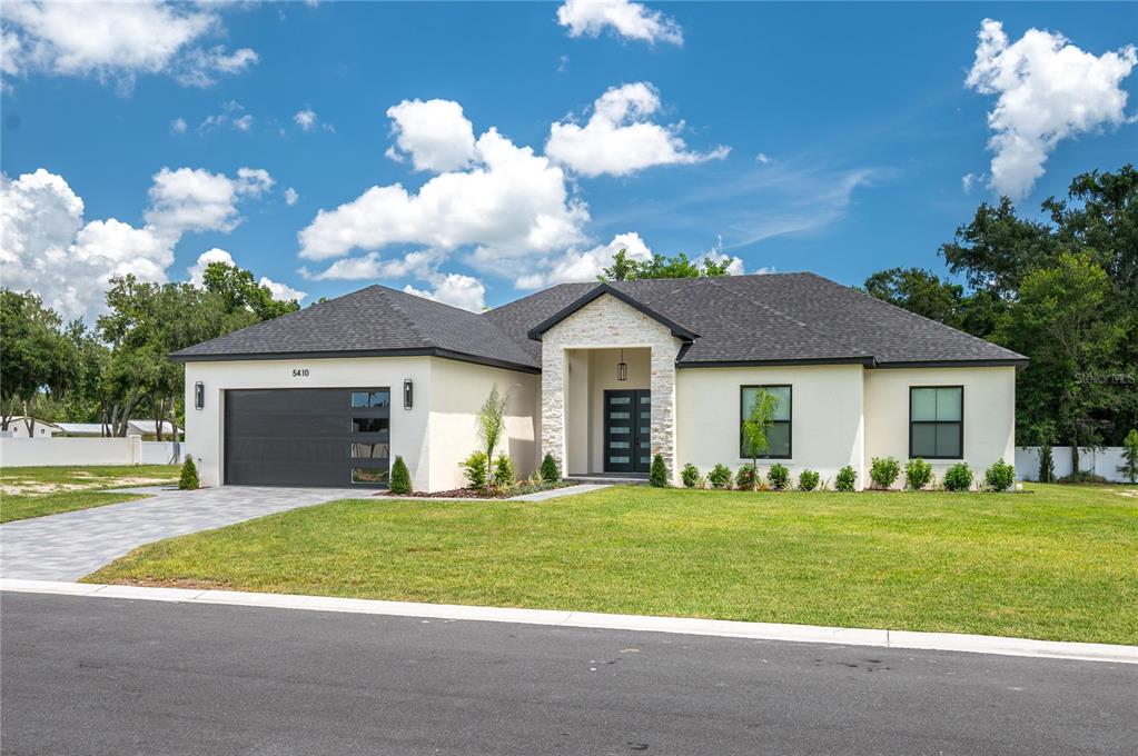 A single-story house with a white stucco exterior, stone entryway, and a two-car garage — 5410 PARKER ESTATES LOOP, LAKELAND, FL