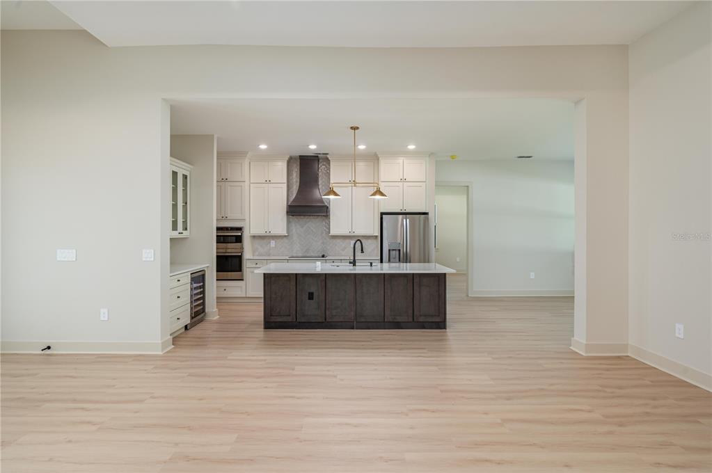 A modern kitchen features white cabinetry, a dark wood island, and light wood flooring — 5410 PARKER ESTATES LOOP, LAKELAND, FL