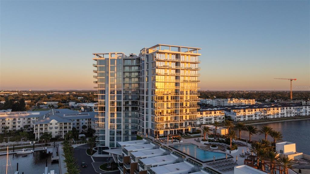 An aerial view of a modern high-rise apartment building with a pool and waterfront docks — 5120 MARINA WAY UNIT 16002, TAMPA, FL