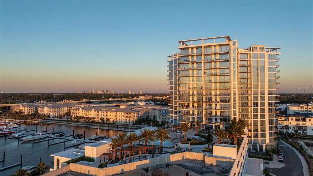 An aerial view of a modern high-rise apartment building next to a marina at sunset — 5120 MARINA WAY UNIT 16002, TAMPA, FL