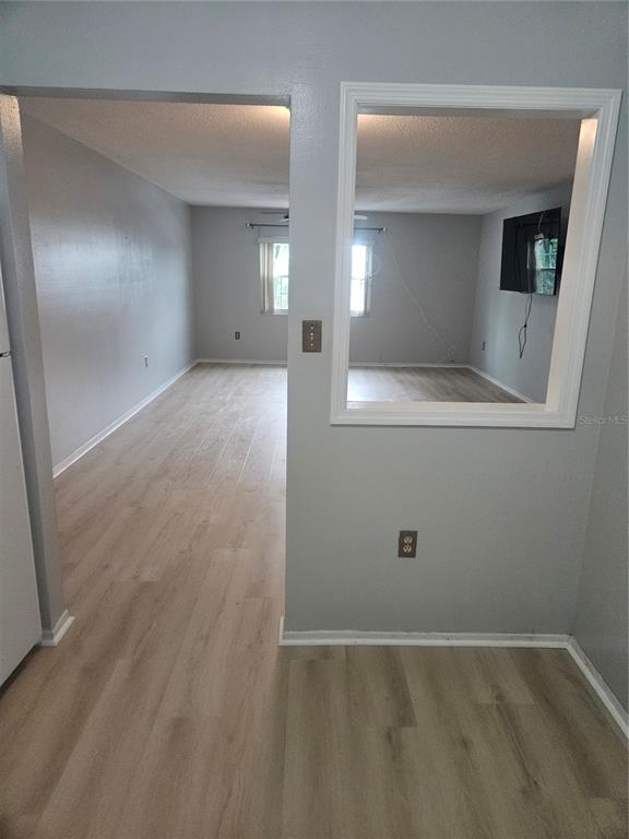 An interior view showing a living area with light wood-look flooring and a pass-through window — 1706 BELLEAIR FOREST DRIVE UNIT 310, BELLEAIR, FL
