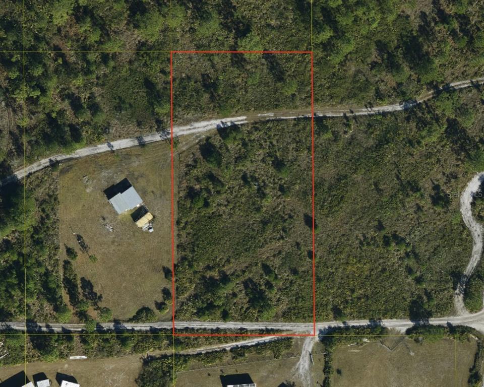 An aerial view shows a rectangular plot of land outlined in red near a dirt road — SUBURBAN ESTS SEC 25...2332 003D, ST CLOUD, FL